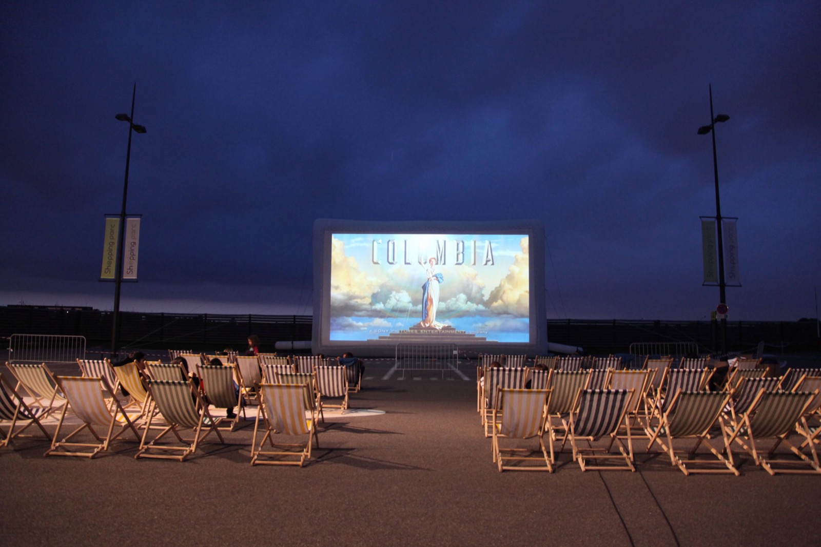 A giant Hallucine inflatable cinema screen set up outdoors, with deckchairs facing the screen as dusk falls